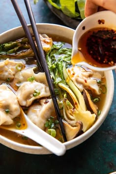 a bowl filled with dumplings and vegetables next to chopsticks