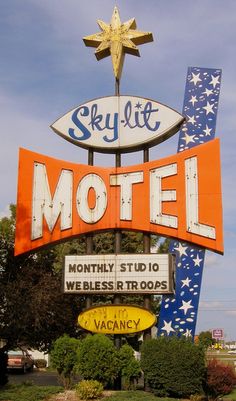 the sky lit motel sign has been painted orange, white and blue with stars on it