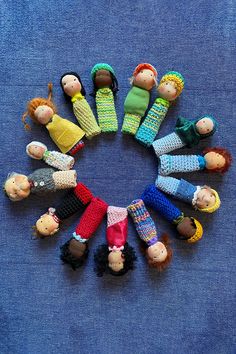 a group of dolls sitting in a circle on top of a blue cloth covered surface