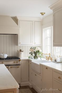 a kitchen with white cabinets and gold hardware on the handles, counter tops and drawers