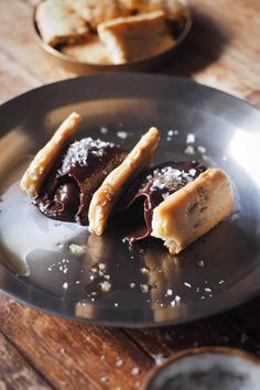 two pastries on a plate with chocolate sauce and sugar sprinkled on them