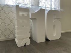 a large white sculpture sitting on top of a wooden floor next to a glass table