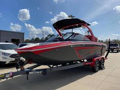 a red and gray boat is being towed by a tow truck in a parking lot