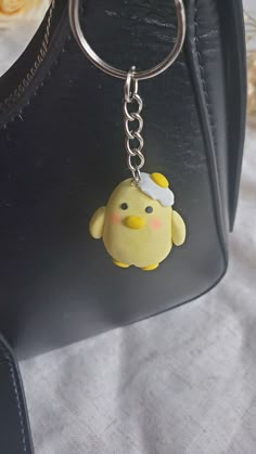 a keychain with a rubber ducky on it's side hanging from a black purse