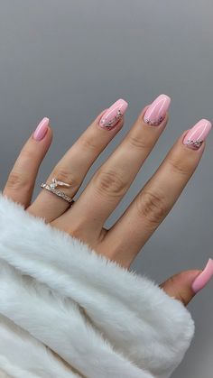 a woman's hand with pink and white manicures on her nails, in front of a gray background