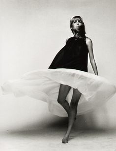 a black and white photo of a woman in a dress with her legs spread out