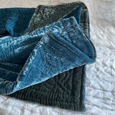 a blue and black blanket laying on top of a bed