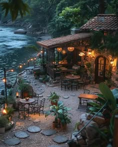 an outdoor dining area with tables and chairs next to the water at night, lit by candles