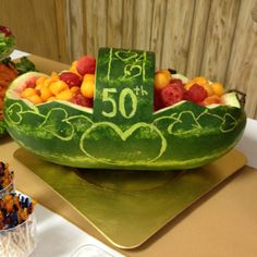 a watermelon boat filled with lots of fruit on top of a wooden table