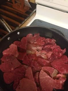 raw meat is cooking in a skillet on the stove