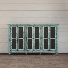 an old wooden cabinet with glass doors on the front and side, against a white wall