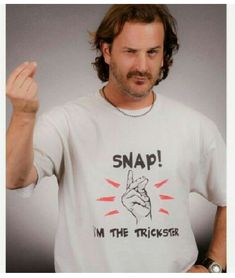 a man with long hair wearing a t - shirt saying snap i'm the trickster