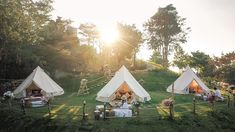 three tents set up in the middle of a grassy field with people sitting at tables