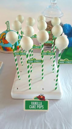 there are many white cake pops on the table with green and white striped straws