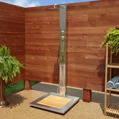 an outdoor shower in the middle of a wooden wall with plants and towels on it