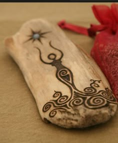 a piece of wood with an intricate design on it and a red ribbon tied around it