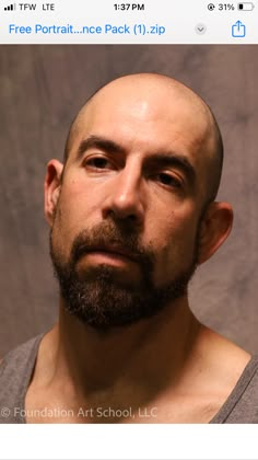 a man with a bald head and beard looking up at the camera while wearing a gray shirt