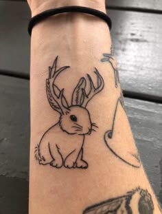 a person with a tattoo on their arm that has an image of a rabbit and music notes