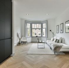 a living room with white furniture and wood floors