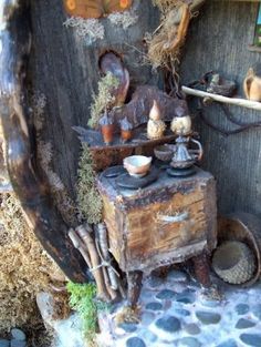 an old fashioned wooden table with pots and pans on it's stand next to a tree trunk