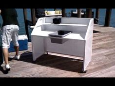 a person walking on a wooden dock next to a white table with a black cup in it