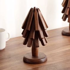 a wooden christmas tree sitting on top of a table next to a white coffee cup