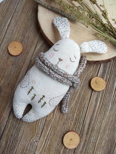 a white stuffed animal sitting on top of a wooden table next to coins and a plant