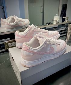 a pair of pink nike shoes sitting on top of a white box in front of a mirror