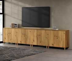 a large flat screen tv mounted to the side of a wooden cabinet in a living room