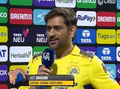 a man holding a microphone in front of a wall with many different logos on it