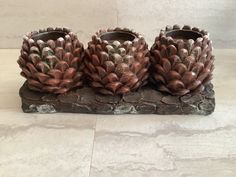 three decorative vases sitting on top of a stone slab in front of a white wall