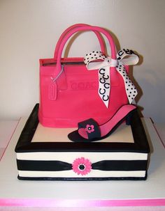 a pink handbag on top of a white and black cake