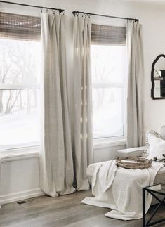 a living room filled with furniture and a window covered in white curtained drapes