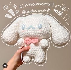 a hand holding a small white crocheted stuffed animal with a pink bow around its neck