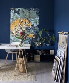 a room with blue walls and pictures on the wall, including a tiger painting in the corner