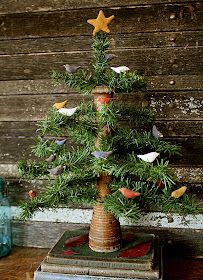 a small christmas tree sitting on top of a stack of books in front of a wooden wall