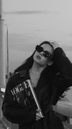 a woman wearing sunglasses and holding a book