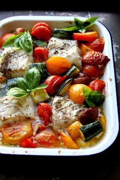 a white dish filled with fish and veggies