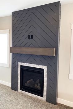 an empty room with a fireplace in the middle and a wall painted black, white and gray