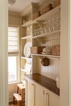 a kitchen with white cabinets and shelves filled with dishes