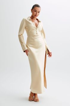 More than a statement, it’s a declaration.This is a long-sleeved maxi dress with a deep collared neckline and centre front button detail. The sleeves end in lined, flared cuffs and the skirt ends in a clean-cut hem with a centre side hem split. The waist is lightly cinched to create a loose hourglass silhouette, further complemented by the soft draped MESHKI blend fabrication. Elegant in its simplicity, this dress is the perfect choice for quick glam. Winter Wishlist, Dresses Date Night, Hourglass Silhouette, Dresses Classy, Mini Wedding, Capsule Outfits, Fitted Shirt, Wedding Guest Dresses, Dress Gold