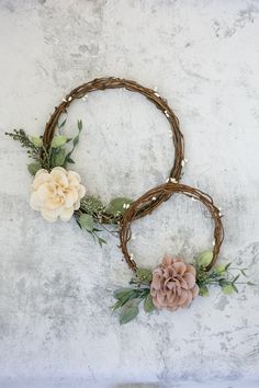 two wreaths with flowers and greenery on them