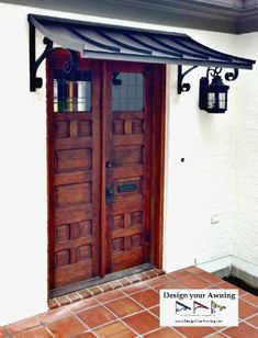 two wooden doors are open in front of a white building with red tile flooring