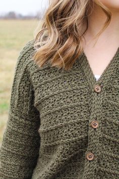 a close up of a woman wearing a green cardigan with buttons on the front