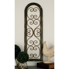 an ornate iron window frame on a shelf next to a potted plant and vase