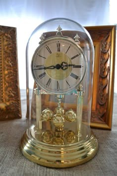 an antique clock under a glass dome on a table