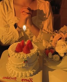 a woman sitting at a table in front of a birthday cake with strawberries on it