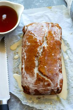 a loaf of bread sitting on top of wax paper next to a cup of tea