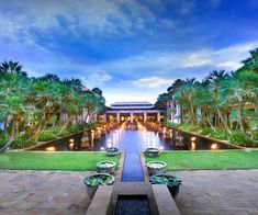 an outdoor pool surrounded by palm trees and water features lights in the center, along with benches on either side