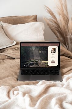 an open laptop computer sitting on top of a bed next to pillows and pillow cases